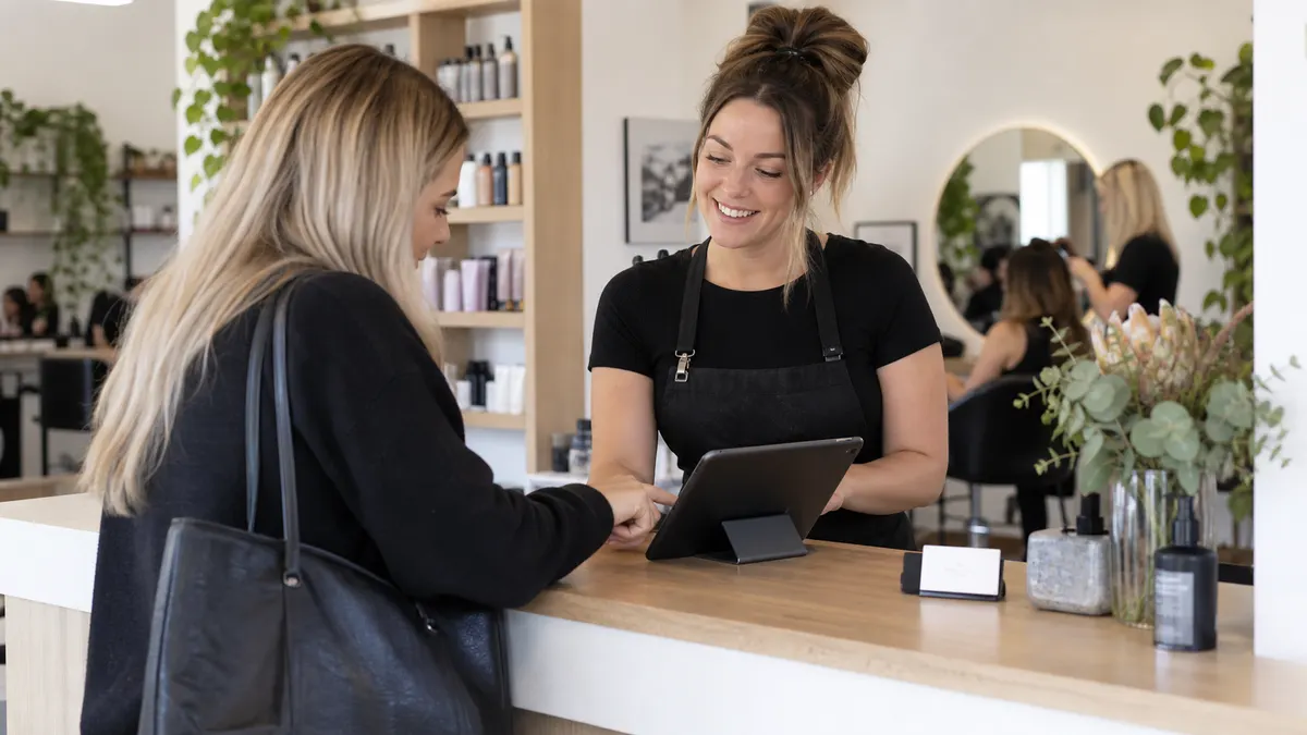 Staff member confirming a customer's contact details on a tablet at the counter.