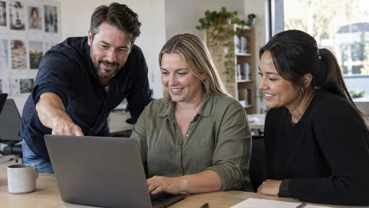 Small business team member training on new CRM software at a desktop computer.